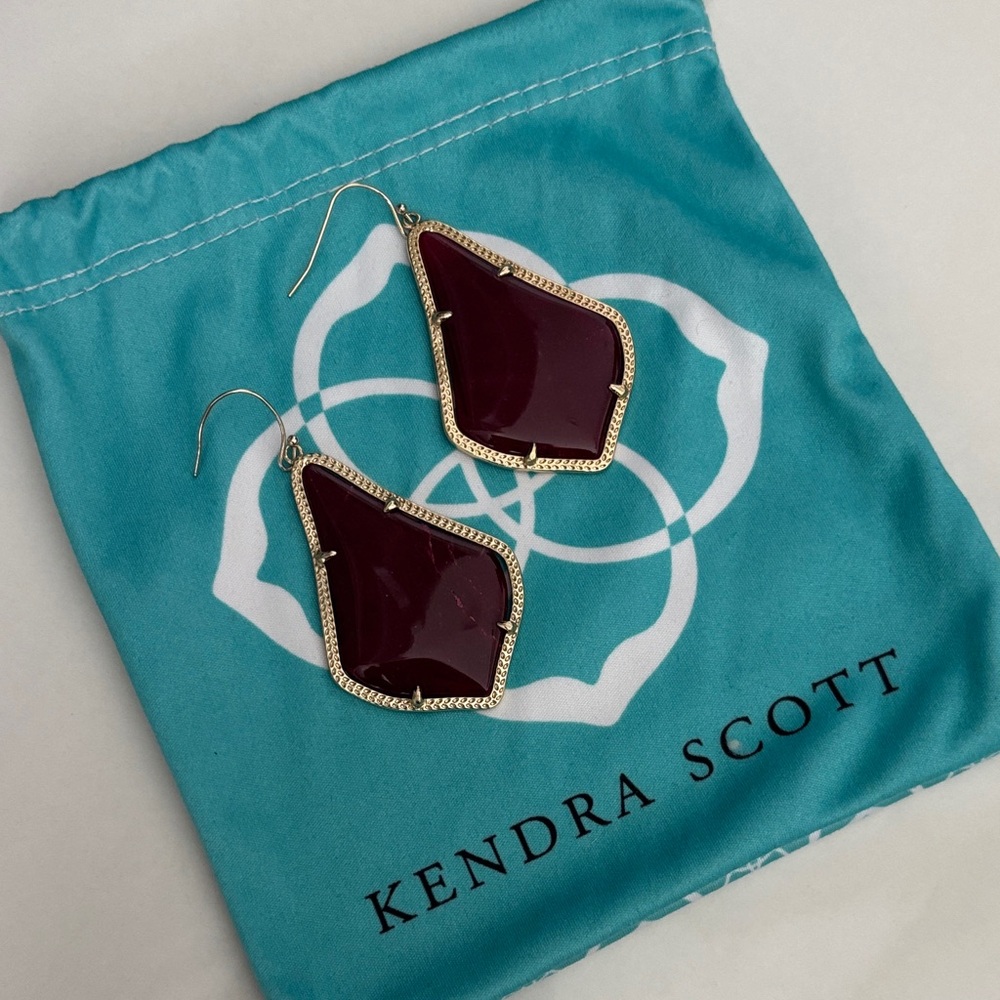 These Kendra Scott Alexandra drop earrings feature dark red opaque glass